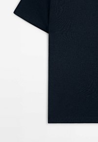 T-shirt noir en coton à manches courtes montré de face sur un fond blanc, mettant en valeur la texture du tissu et les détails de l'ourlet.