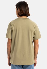 Camiseta de manga corta verde oliva con un corte relajado, material de algodón suave y un clásico escote redondo. Presenta una pequeña etiqueta cerca del dobladillo.