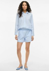 Blue and white striped button-up shirt paired with matching shorts. The outfit features a relaxed fit, soft fabric, and a casual design.