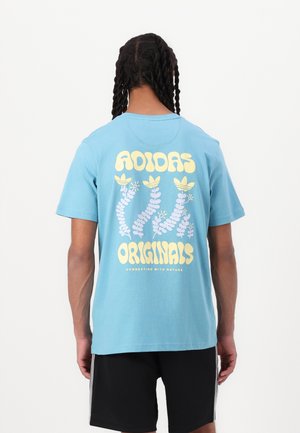 Svetlomodré bavlnené tričko s veľkým žltým a purpurovým grafickým motívom na chrbte s textom "ADIDAS ORIGINALS" a rastlinnými prvkami.