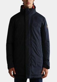 Giacca a vento navy con colletto alto, zip frontale e tasche. Presenta un rivestimento arancione a contrasto e una patch con il logo sulla manica.