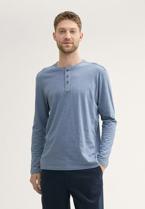 Langärmliges blaues Henley-Shirt aus weichem Stoff, mit einem vierknöpfigen Ausschnitt, rundem Halsausschnitt und normaler Passform.