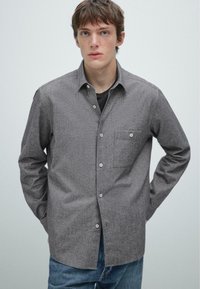 Grijze overhemd met een gestructureerde stof, enkele borstzak en klassieke kraag, gecombineerd met blauwe spijkerbroek.