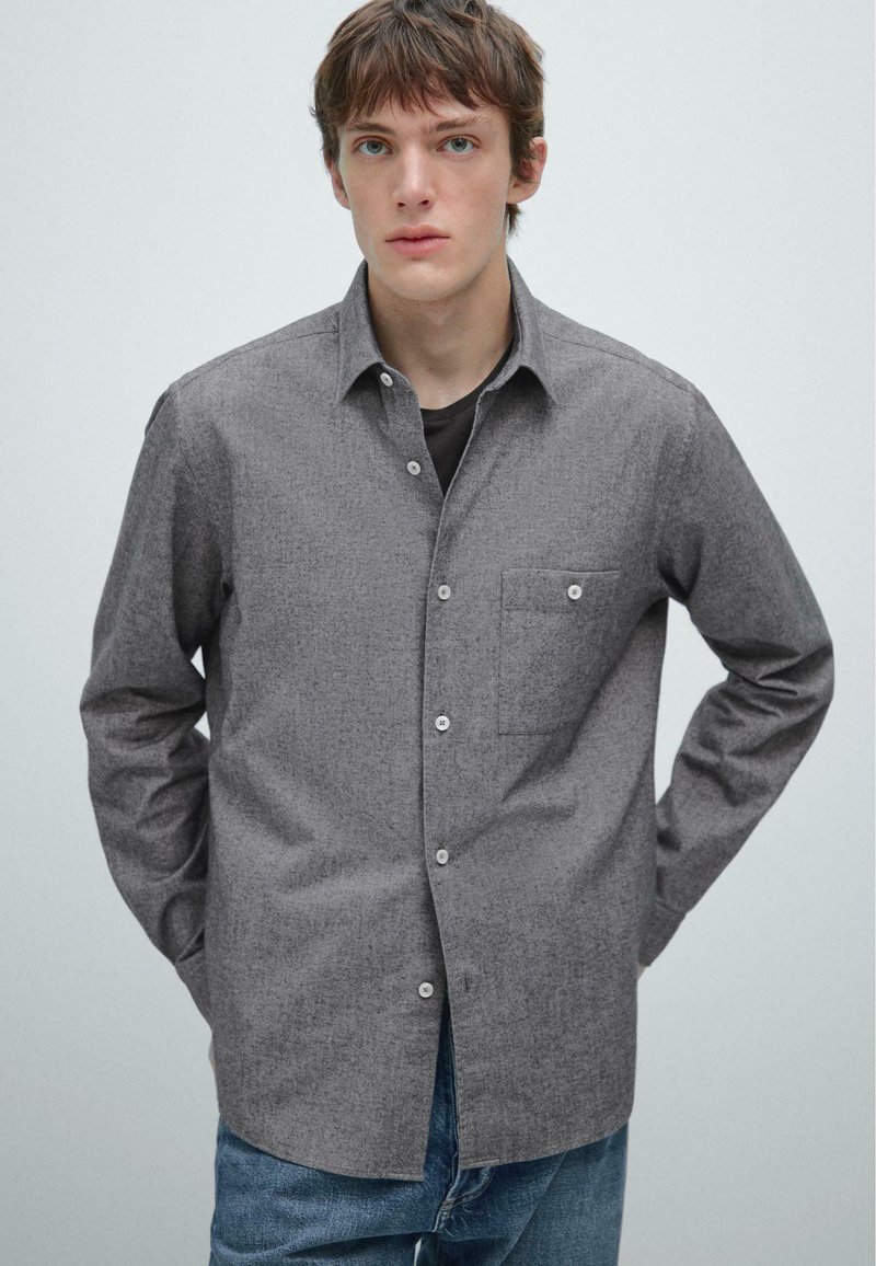 Grijze overhemd met een gestructureerde stof, enkele borstzak en klassieke kraag, gecombineerd met blauwe spijkerbroek.
