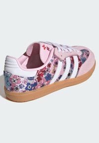 Sneaker in suede rosa con motivo floreale e strisce bianche. Presenta una suola in gomma naturale e un colletto imbottito per il massimo comfort.