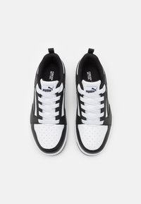 Black and white sneakers with a smooth leather and textile upper, perforated front, white laces, and a prominent logo on the tongue.