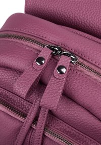 Sac en cuir texturé violet avec double fermeture à glissière et fermoirs à languette. Présente des dents de fermeture à glissière visibles et un haut lisse et arrondi.