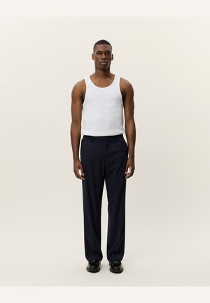 White tank top and navy trousers, smooth fabric, straight leg design, minimalistic style, paired with dark shoes, front view.