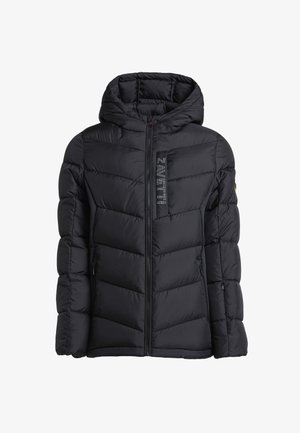 Zwarte pufferjack met capuchon, ritsluiting en logo patch. Draagt over een zwart shirt en zwarte sweatpants, aangevuld met zwarte sneakers.