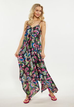 Robe noire fluide avec un motif paisley coloré, bretelles spaghetti et ourlet asymétrique. Assortie avec des sandales roses vives.