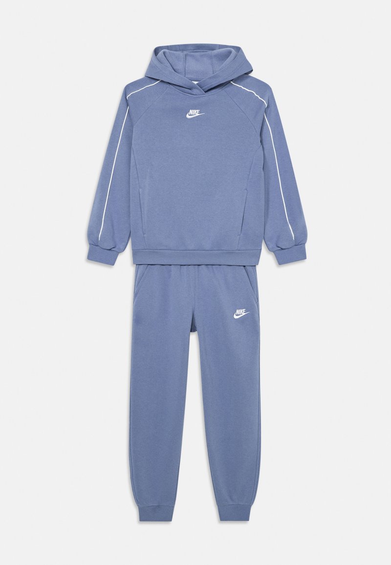 Nike divdaļīgs treniņtērps gaiši zildā krāsā. Kapuce ar raglanu piedurknēm un balto logotipu; atbilstošas bikses ar elastīgu jostu un logotipu.