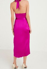 Robe midi sans bretelles de couleur rose vif avec une finition satinée, dotée d'un nœud noué à l'arrière et d'une silhouette ajustée qui s'évase jusqu'à l'ourlet.