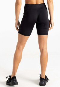 Schwarze Sportshorts aus dehnbarem Material mit einem hohen Taillenbund und einem eng anliegenden Design, das bis zur Mitte des Oberschenkels reicht. Schwarze Sneakers inklusive.