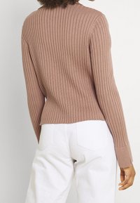 Geribbelde gebreide trui in stofroze, met een aansluitend model, ronde hals en lange mouwen, gecombineerd met een witte broek met hoge taille.