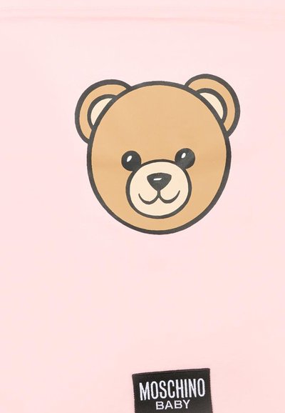 Lichtroze stof met een cartoonbeertjes gezicht in bruin, zwart en wit, met een zwart etiket "Moschino Baby" aan de onderkant.