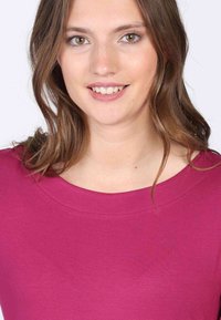 Fuchsia Rundhalsoberteil aus glattem Stoff mit kurzen Ärmeln und einem lockeren Schnitt. Keine auffälligen Akzente oder Muster.