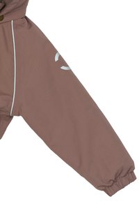 Ruskea vedenpitävä takin hiha joustavalla hihansuutuksella, heijastavilla yksityiskohdilla ja sileällä pinnalla. Saumadetaljit pitkin käsivartta.