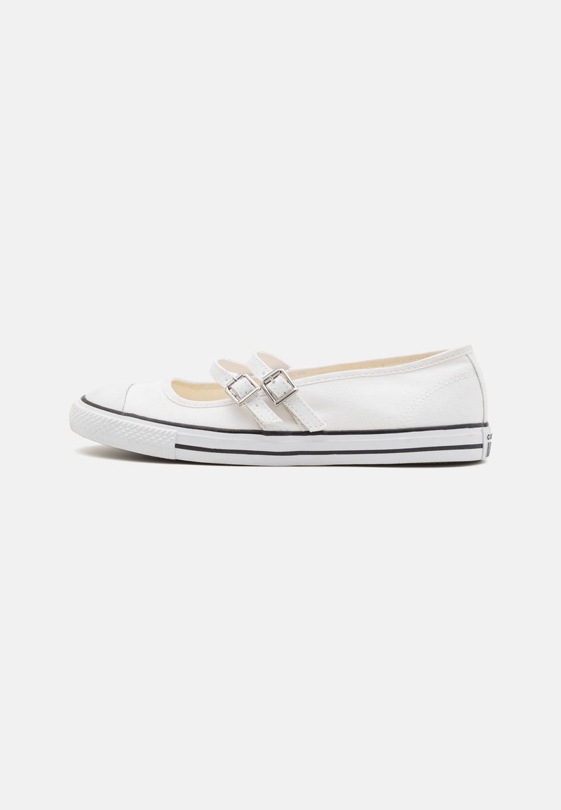 Zapatillas Mary Jane de lona blanca con correas doble hebilla y suela de goma a rayas negras sobre fondo blanco liso.