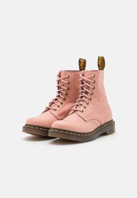 Pink leather ankle boots with round toes, lacing, yellow stitching, and pull tabs. Smooth texture and rubber soles.