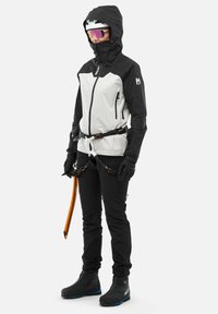 Weatherproof climbing jacket in black and white, featuring a hood, zippers, and adjustable belt; paired with black climbing pants and footwear.