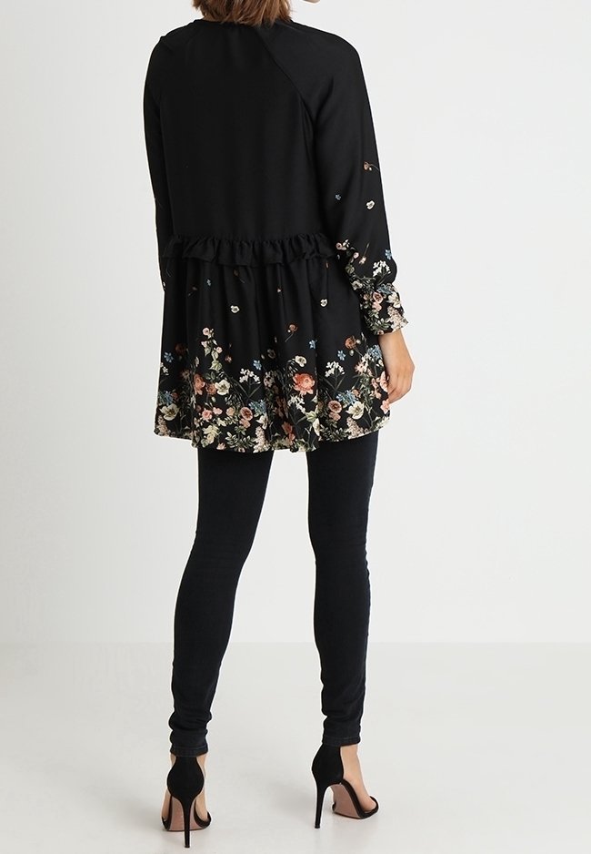 Svart tunika med blommönster vid fållen, volang i midjan och långa ärmar. Matchas med svarta skinny jeans och klackar.