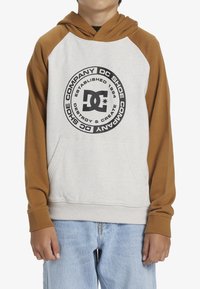Sudadera con capucha de color crema en el cuerpo y mangas marrones. Presenta un gran logo negro en el frente y un bolsillo tipo canguro en el frontal.