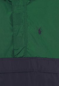 Grön och marinblå färgblockerad jacka i lätt, slätt tyg. Har en liten broderad logotyp och förstärkta sömdetaljer.