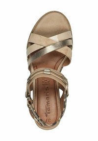 Sandal beige con cinturini incrociati, accenti metallici e una soletta testurizzata. Presenta una suola piatta e liscia con un cinturino al tallone con stampa leopardata.