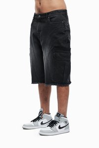 Shorts cargo en denim noir avec un ourlet effiloché, dotés de poches latérales et de coutures courbes. Portés avec des baskets montantes grises et blanches.
