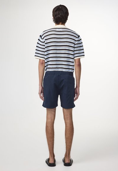 Randig stickad kortärmad tröja i blått, vitt och svart. Matchad med marinblå shorts med elastiskt midjeband och plånboksficka.
