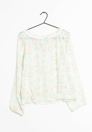 Blusa leggera verde con maniche lunghe, scollatura off-shoulder e motivi a raggiera ripetuti in beige. Finitura con un nodo al collo.
