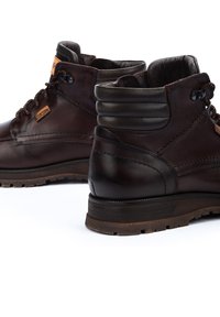 Bottines en cuir marron avec une finition lisse, bout rond et col rembourré ; dotées d'un laçage à l'avant et d'une semelle en caoutchouc texturée.