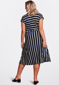 Striped dress featuring short sleeves, a fitted waist, and a flared skirt in black, blue, and yellow stripes. Worn with black sandals.