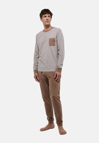 Chemise grise à manches longues avec une poche poitrine en cuir marron et un pantalon marron assorti, tous deux en tissu doux, avec des poignets et une taille élastiques.