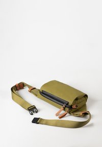 Olive green rectangular waist bag with black zipper and leather zipper pulls, adjustable strap, and black plastic buckle, on white background.