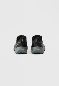 Zwarte wandelschoenen met een gestructureerd bovenwerk, een grijze Vibram-zool, verstevigde hiel en merkopdruk aan de zijkant. Lichtgewicht en duurzaam ontwerp.