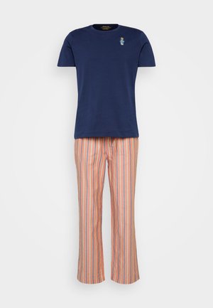 Tumši zils kokvilnas t-krekls ar nelielu izšūtu dizainu, apvienots ar oranžiem svītrainiem, platajiem pidžamu biksēm, kas izgatavotas no viegla auduma.