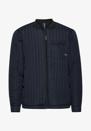 Giacca bomber trapuntata blu navy con colletto a coste nero, chiusura frontale con zip e tasca sul petto con zip; presenta cuciture orizzontali e un'etichetta con logo.