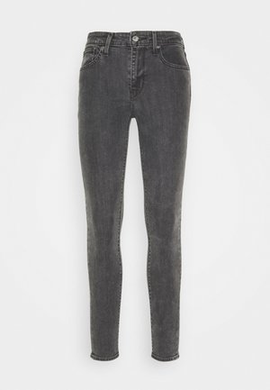 Jeans skinny en denim gris foncé, avec un design classique à cinq poches, passants de ceinture et fermeture à bouton. Texture lisse avec un léger délavage.