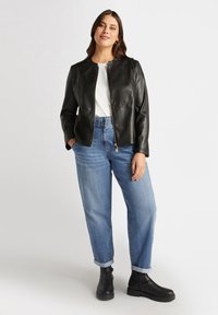 Black leather jacket with a round neckline and zip closure. Paired with light blue relaxed-fit jeans and black ankle boots.