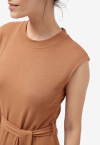 Brun strikket kjole med korte ærmer, der har en rund halsudskæring og et stofbælte bundet i taljen. Glat tekstur og strømlinet design.