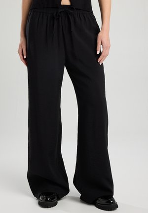 Mustat leveälahkeiset housut, joissa on teksturoitu pinta, joustava vyötärö ja nyöri. Kangas on kevyen näköinen ja sileäpintainen.