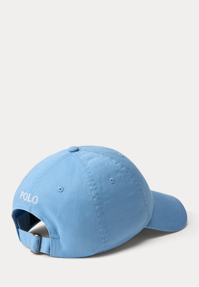 Lyseblå baseballkasket med justerbar rem og "POLO" broderet i hvid på bagsiden, vist fra en bagfra sidevinkel.