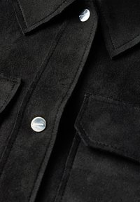 Svart mockajacka med krage, två bröstfickor med lock och silverfärgade tryckknappar längs fram.