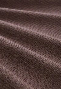 Bruine textuurstof met fijne ribbel, die zachte golven en subtiele variaties in kleur en textuur over het oppervlak toont.