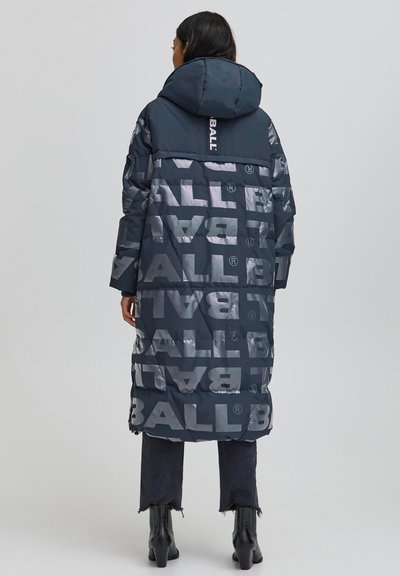 Jūras flotes krāsas polsterēta virsjaka ar izteiktu "BALL" logotipu gaiši pelēkā krāsā. Aprīkota ar kapuci, garām piedurknēm un garumu zem ceļgala. Redzamas melnas džinsu bikses un zābaki.