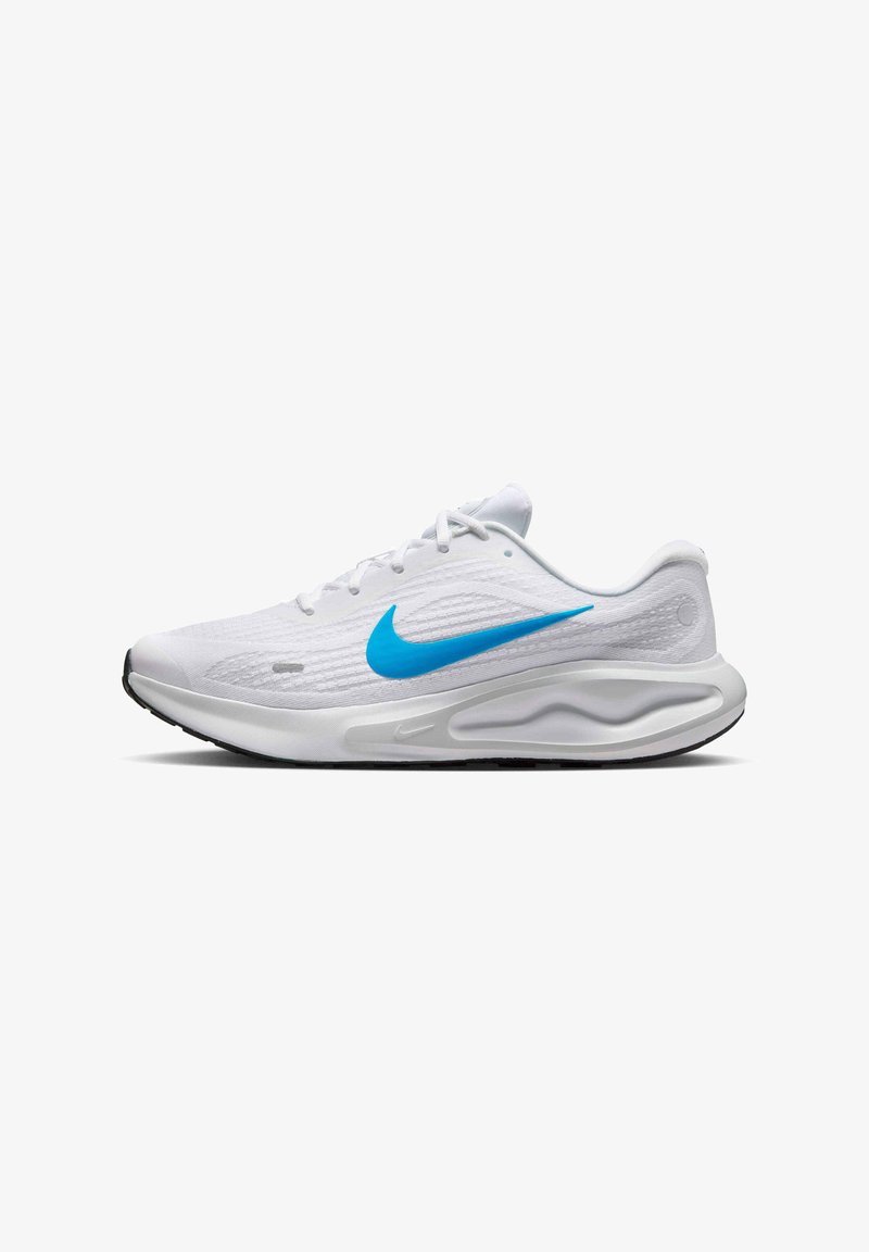 Baskets blanches avec un dessus texturé, logo Swoosh bleu, semelle intermédiaire rembourrée et semelle extérieure en caoutchouc noir. Les lacets sont blancs.
