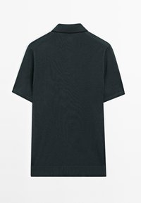 Mörkgrön kortärmad polo-shirt med krage, med en slät yta och subtila sömnadsdetaljer. Inga synliga logotyper eller mönster.