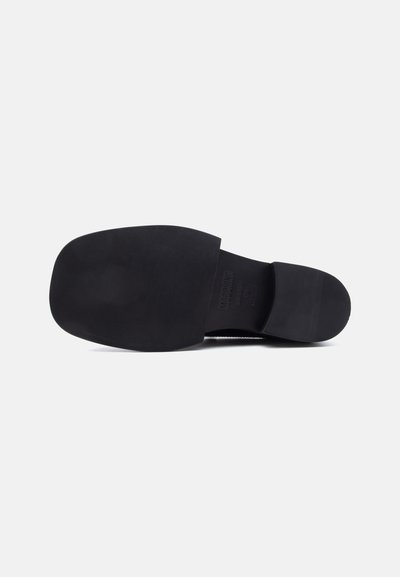 Semelle de chaussure noire avec bout carré et grip texturé, nom de la marque visible et indications de taille au centre.