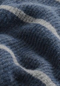 Zachte, gestructureerde gebreide stof in donkerblauw met lichtgrijze golvende strepen. Het materiaal lijkt pluizig en gezellig, met een geribbelde structuur.